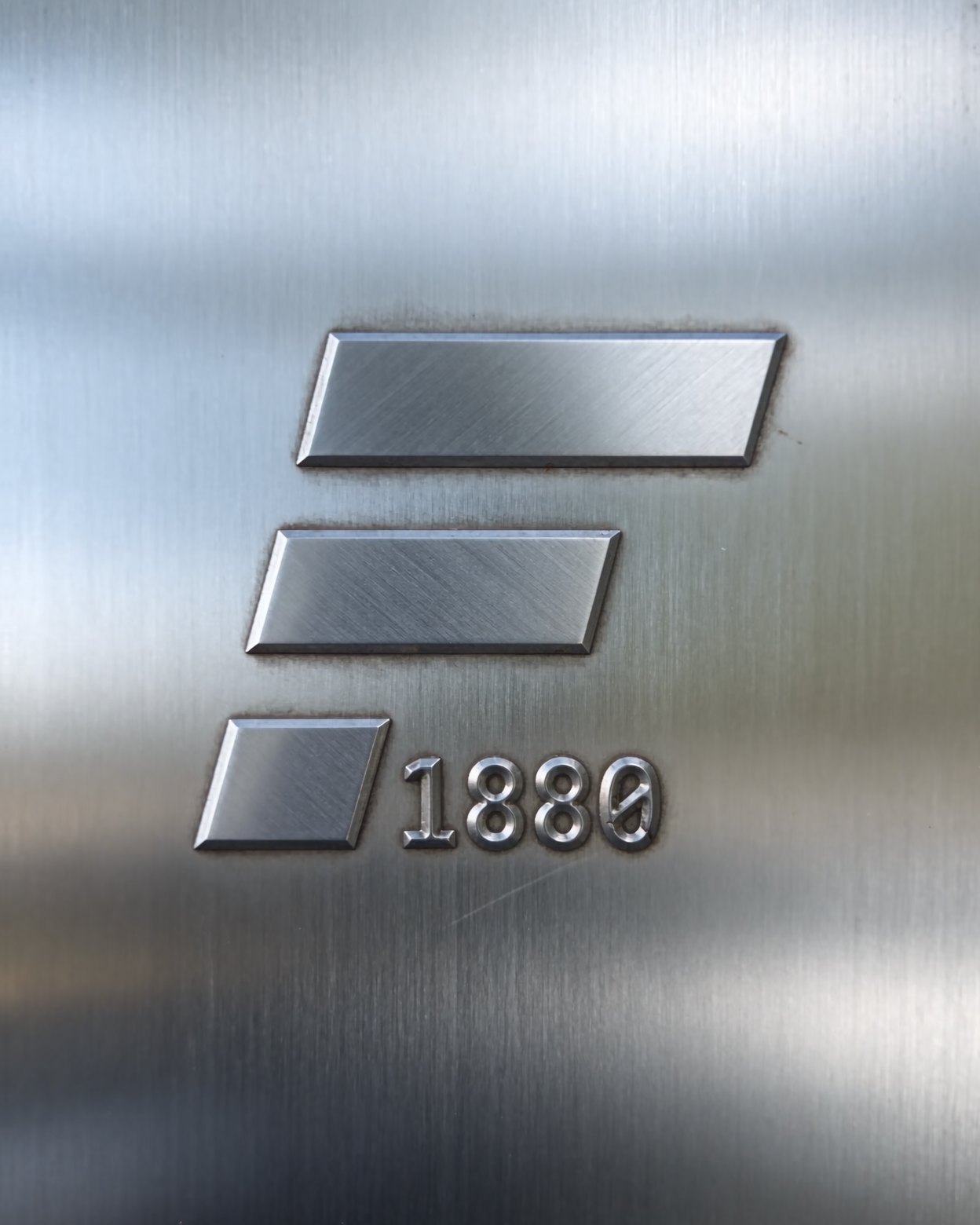 The F1880 mark in relief on a steel plate: mill scale and rust fall away, bright brushed steel remains.