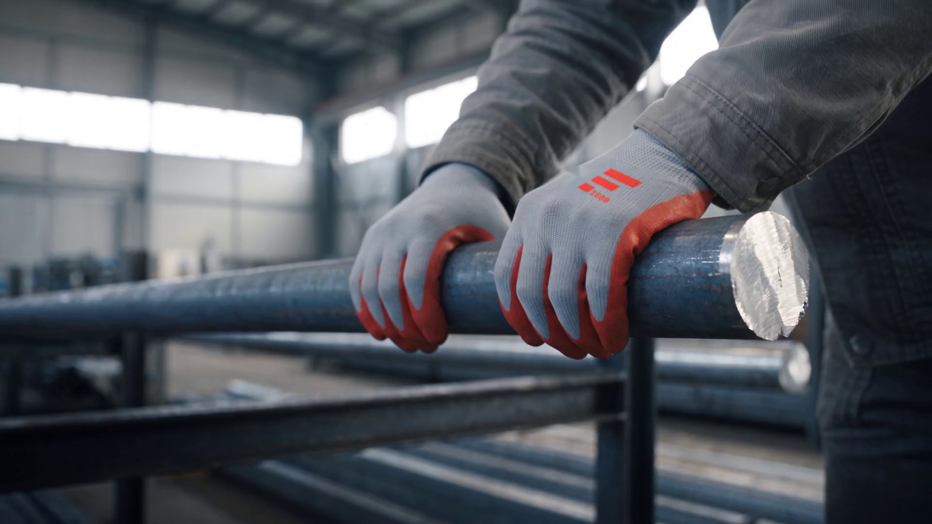 Hands in work gloves with the FRANKSTAHL mark lift a round steel bar.